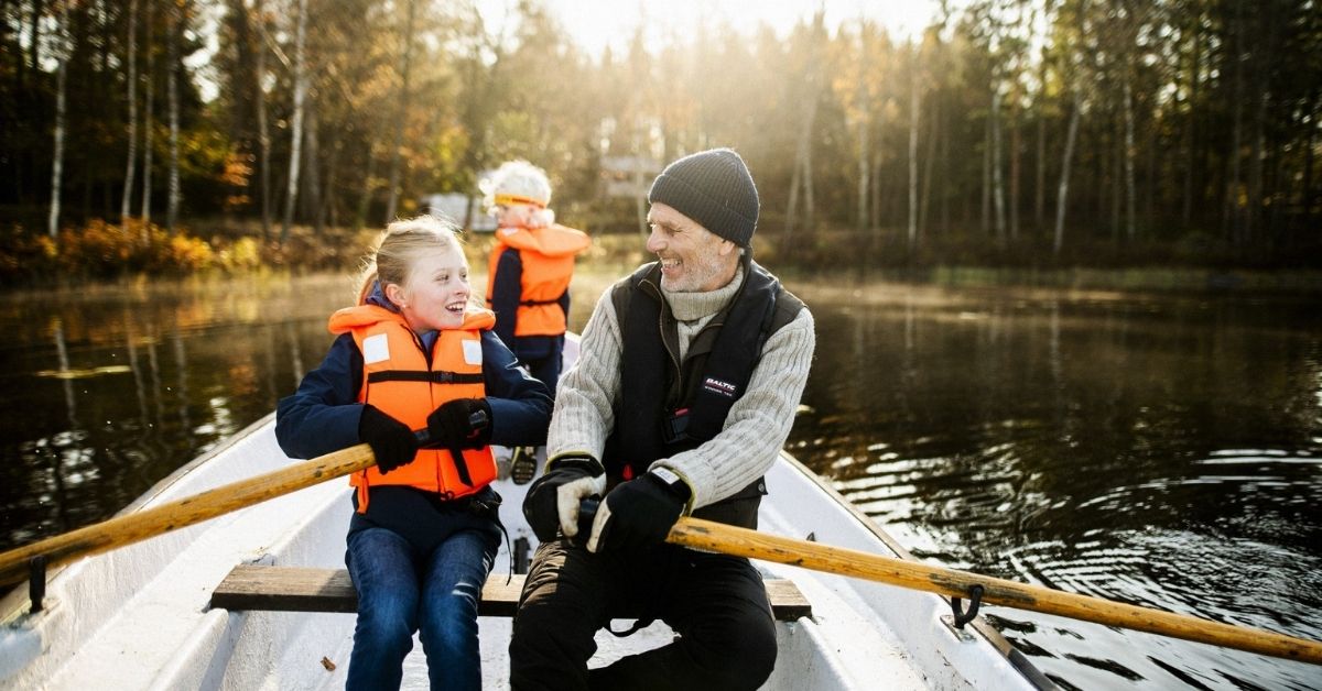 Familj njuter av en höstutflykt i Blekinge – roddtur på sjön omgiven av färgsprakande skog.