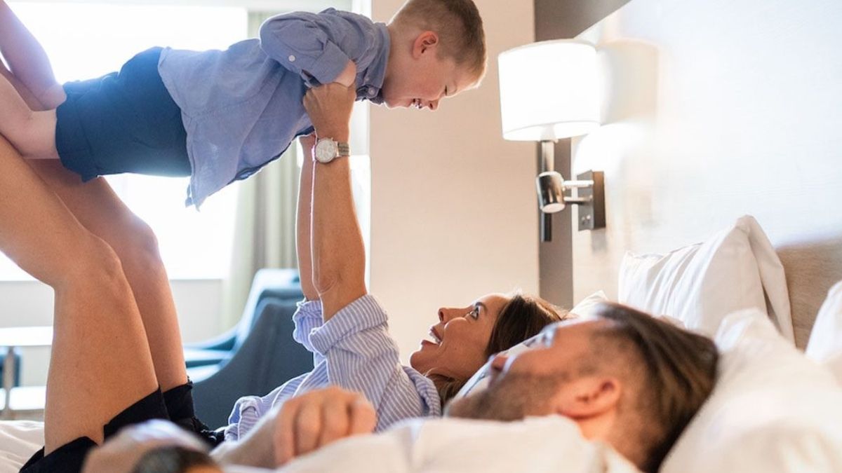 Lycklig familj i hotellrum på Ronneby Brunn - föräldrar leker med barn i sängen