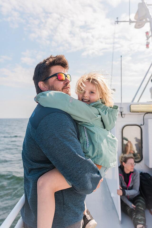 Pappa bär dotter i famnen på båtens däck