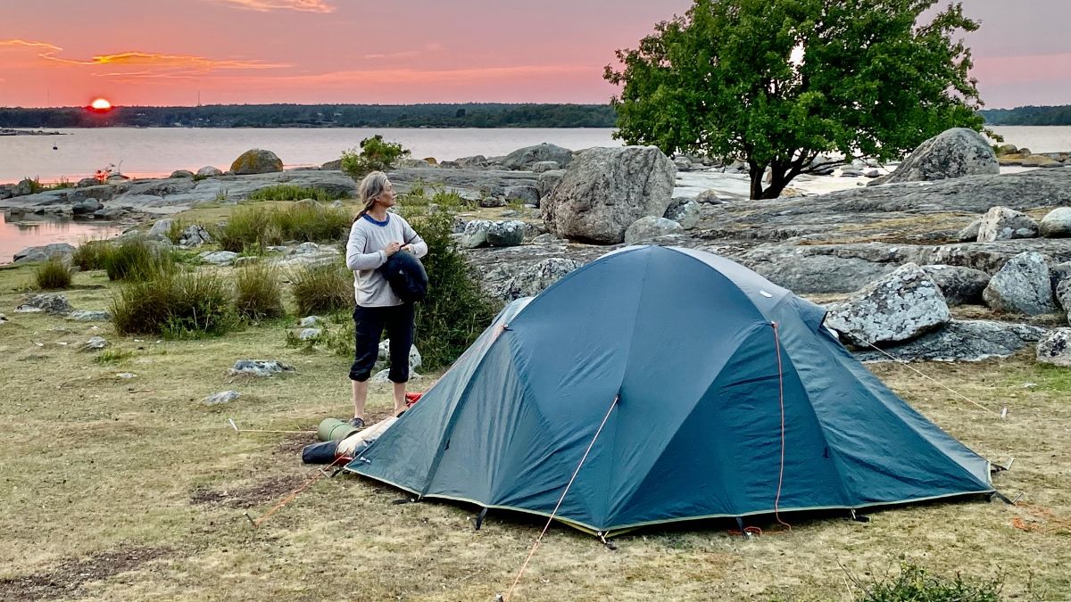 Tältcamping vid Blekinges skärgård i solnedgången, med vy över klippor, hav och kvällshimlen.