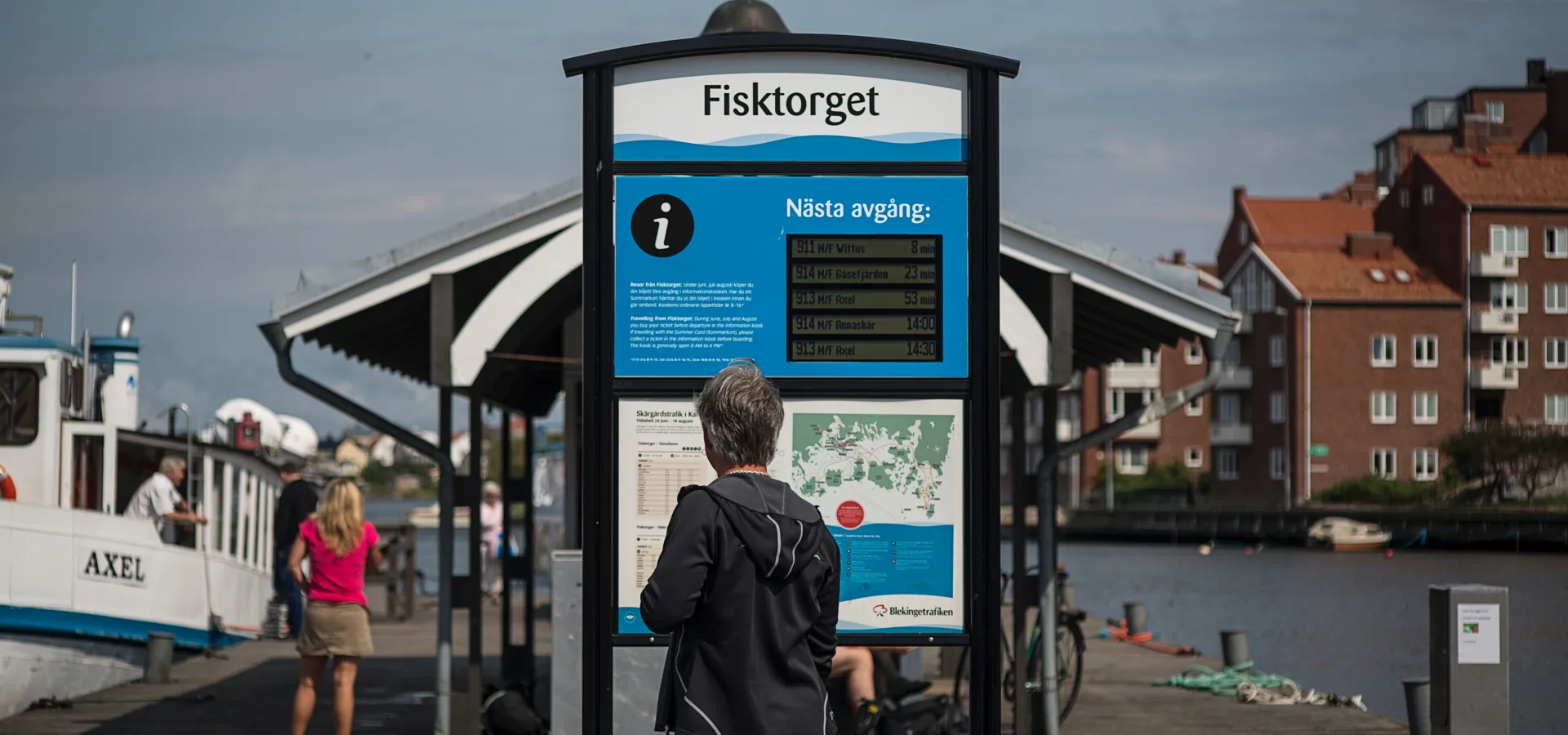 Fisktorget Karlskrona - man som läser tidtabell till akrägårdsbåtarnas turer 
