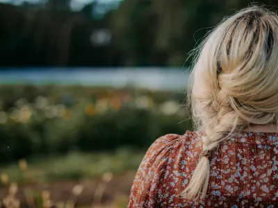 Ung tjej spanar ut över en sommaräng.