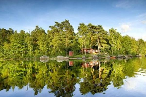 Trees and cottages are reflected in the lake