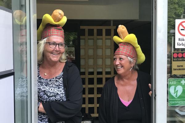 Two women, each with a hot dog hat on their heads